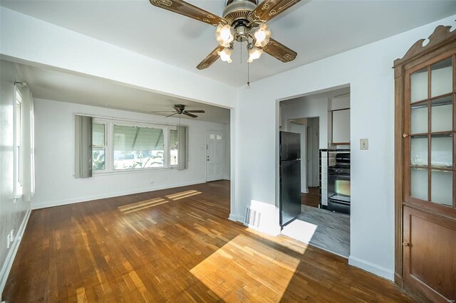 interior space with a ceiling fan, baseboards, visible vents, and wood finished floors