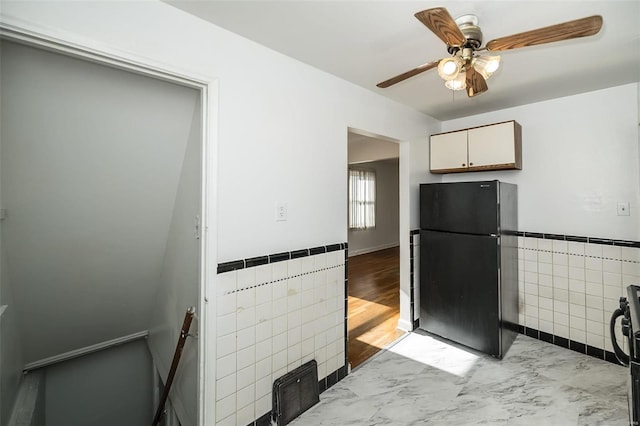 kitchen with black refrigerator, light hardwood / wood-style flooring, range, tile walls, and ceiling fan