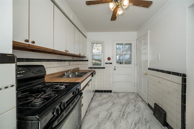 kitchen with white appliances, sink, ceiling fan, tile walls, and white cabinets