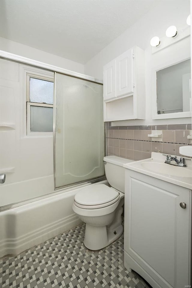 full bathroom featuring vanity, toilet, tasteful backsplash, and bath / shower combo with glass door