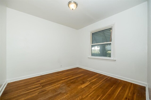 empty room with baseboards and dark wood-style flooring