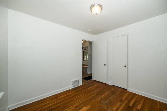 unfurnished bedroom featuring dark wood-style flooring, baseboards, and visible vents