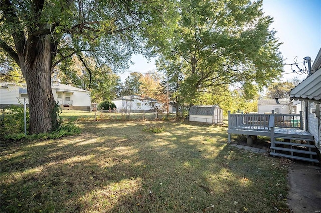 view of yard featuring a wooden deck and a storage shed