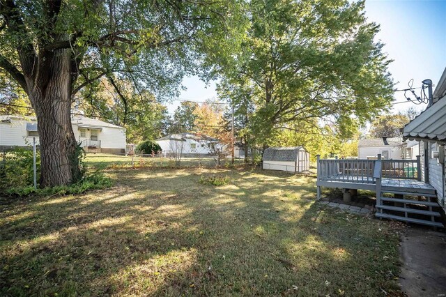 view of yard with fence, an outdoor structure, a deck, and a storage shed