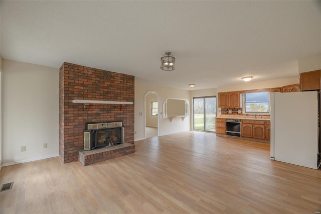 unfurnished living room with light hardwood / wood-style floors, sink, and a brick fireplace