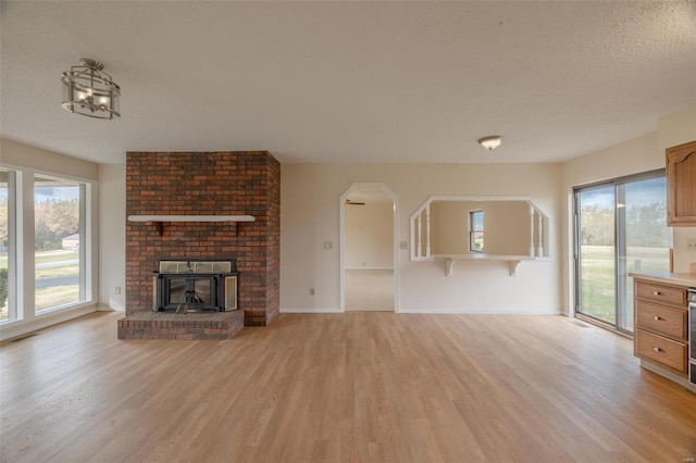 unfurnished living room featuring a textured ceiling, a fireplace, and light wood-type flooring