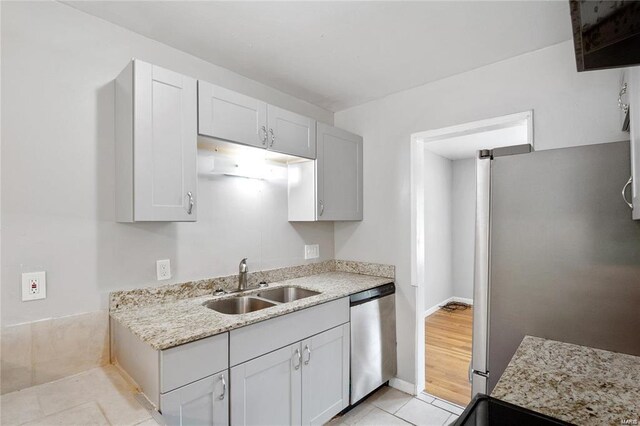 kitchen featuring sink, light stone countertops, white cabinets, appliances with stainless steel finishes, and light hardwood / wood-style floors