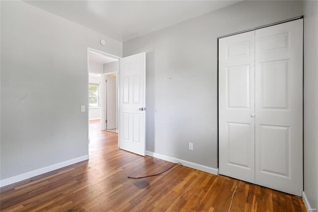 unfurnished bedroom with dark wood-type flooring and a closet