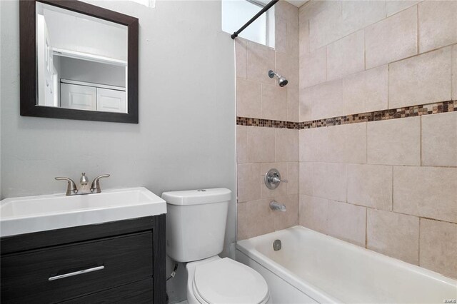 full bathroom with tiled shower / bath, vanity, and toilet