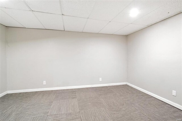 carpeted empty room with a drop ceiling