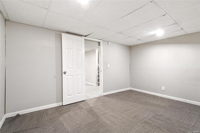 basement with a paneled ceiling and carpet