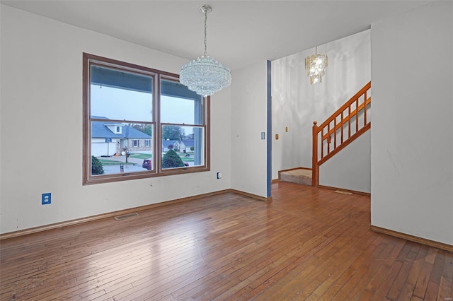 empty room with hardwood / wood-style flooring and a notable chandelier