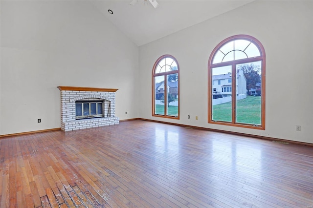 unfurnished living room featuring a brick fireplace, hardwood / wood-style floors, ceiling fan, and high vaulted ceiling