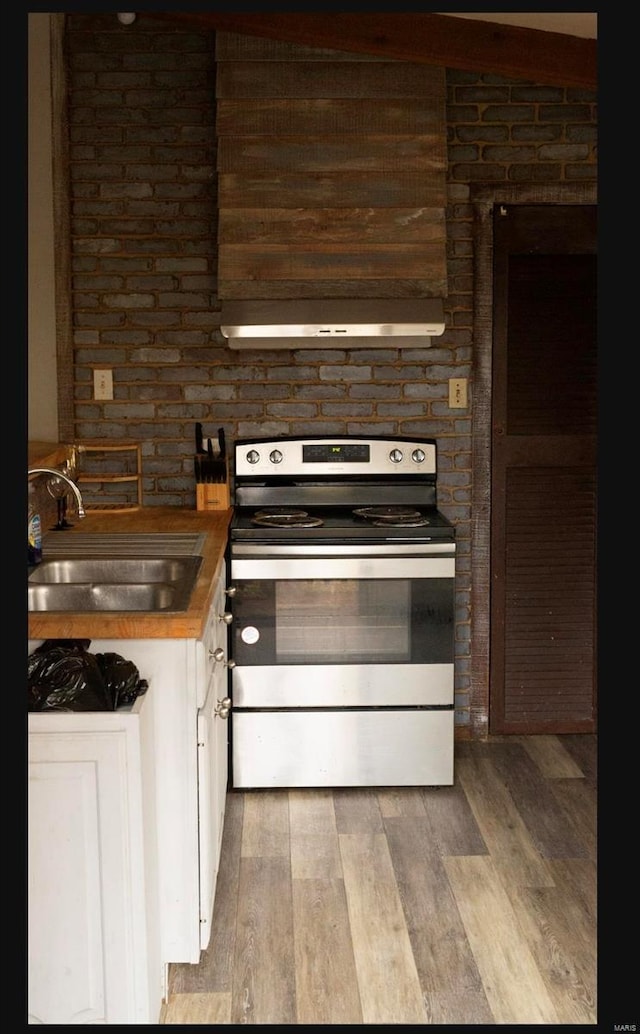 kitchen with light hardwood / wood-style flooring, sink, stainless steel range with electric cooktop, and butcher block countertops