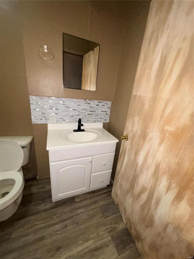 bathroom featuring wood-type flooring, vanity, toilet, and tasteful backsplash