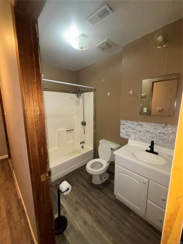 full bathroom featuring washtub / shower combination, tasteful backsplash, wood-type flooring, vanity, and toilet