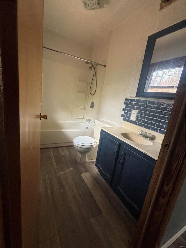 full bathroom with wood-type flooring, toilet, decorative backsplash, shower / bathing tub combination, and vanity