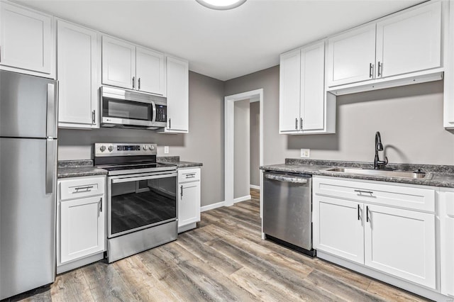 kitchen featuring hardwood / wood-style flooring, stainless steel appliances, white cabinetry, and sink