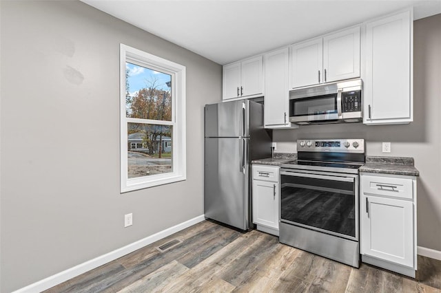 kitchen with stainless steel appliances, dark hardwood / wood-style floors, and white cabinets