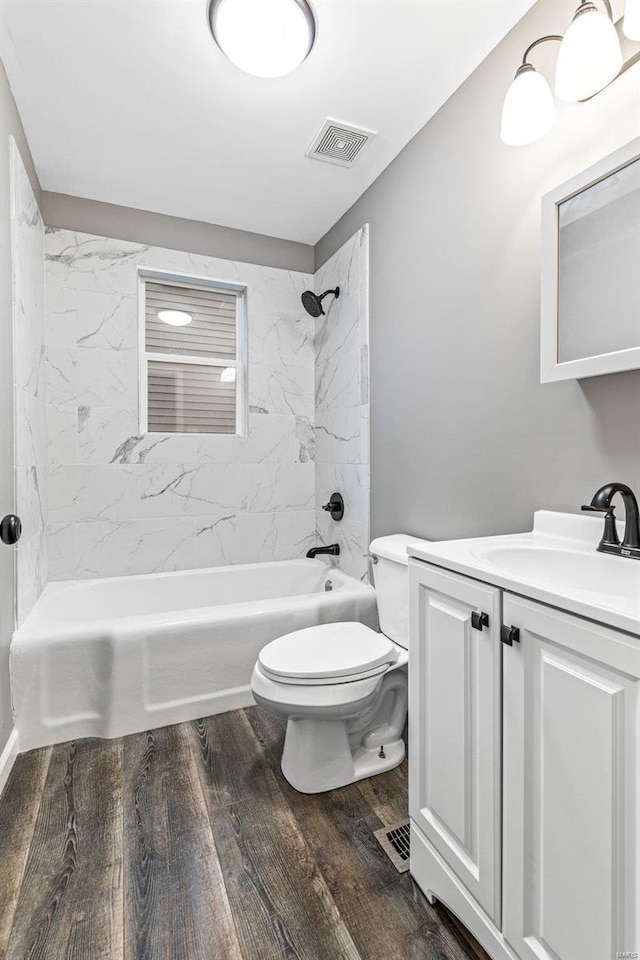 full bathroom with hardwood / wood-style floors, vanity, tiled shower / bath combo, and toilet