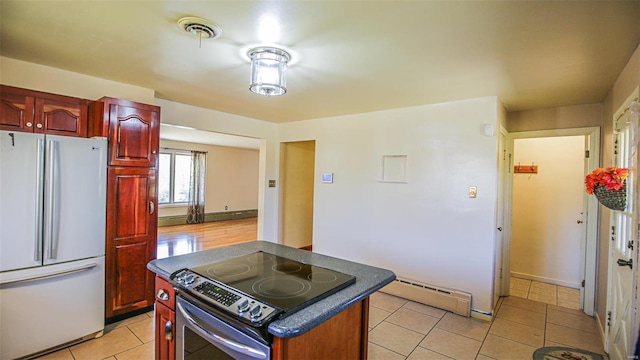 kitchen featuring a center island, stainless steel electric range, light tile patterned flooring, white refrigerator, and a baseboard radiator