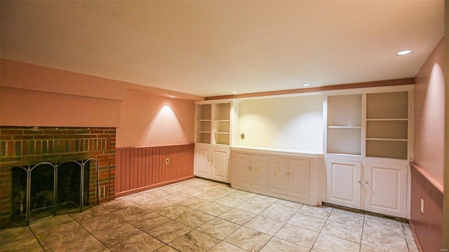 unfurnished living room featuring a brick fireplace and built in shelves