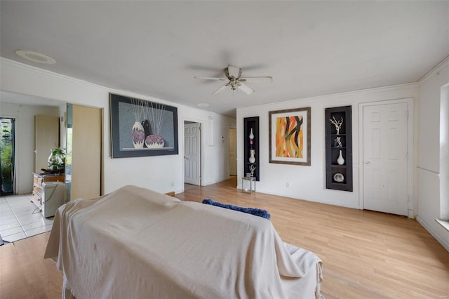 bedroom with ornamental molding, light wood-type flooring, and ceiling fan