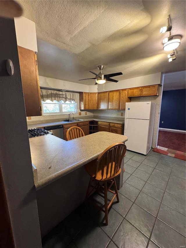 kitchen featuring dishwasher, kitchen peninsula, ceiling fan, tile patterned floors, and white refrigerator