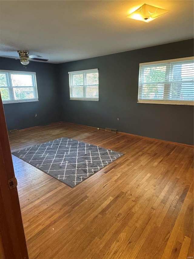 unfurnished room featuring hardwood / wood-style floors, a healthy amount of sunlight, and ceiling fan