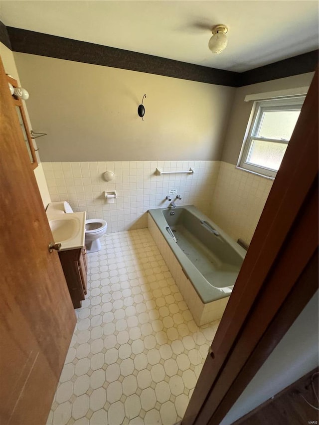 bathroom featuring vanity, a tub, tile walls, and toilet