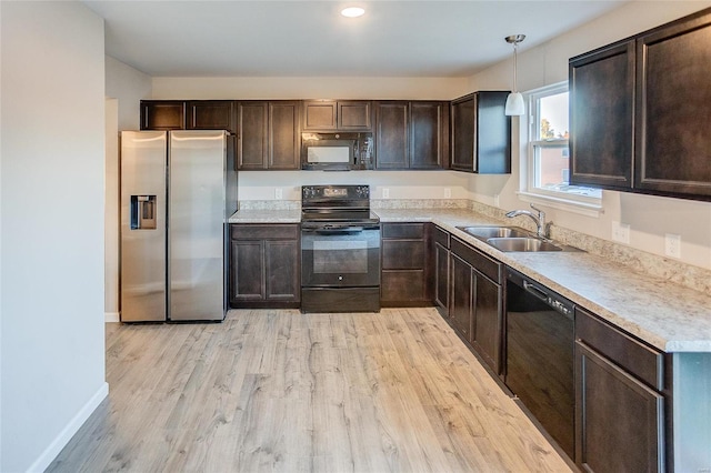 kitchen featuring sink, hanging light fixtures, dark brown cabinets, black appliances, and light wood-type flooring