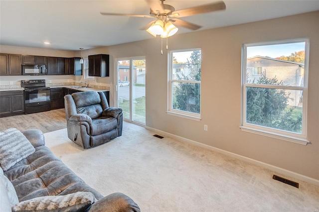 carpeted living room with ceiling fan and sink