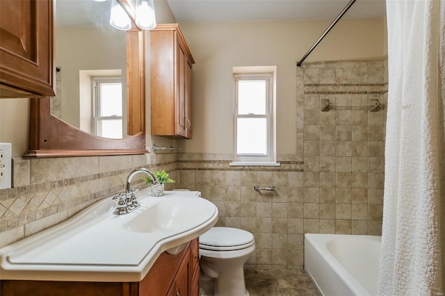 full bathroom with shower / bath combo, toilet, tile walls, vanity, and tile patterned flooring