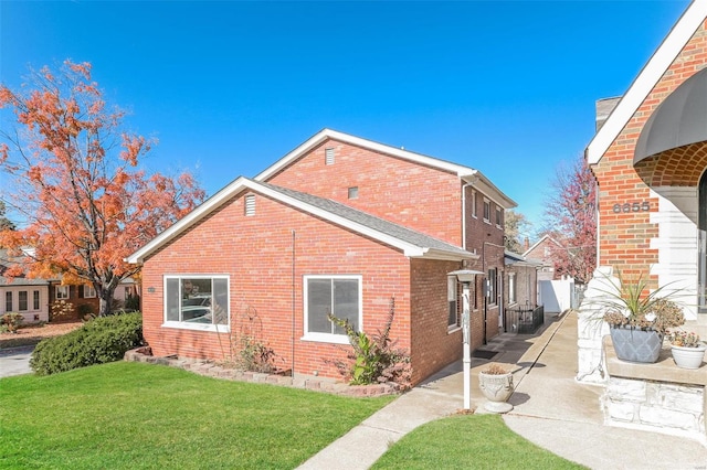 view of side of home with a patio and a lawn