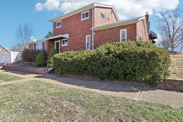 view of property exterior with a yard, brick siding, and a chimney