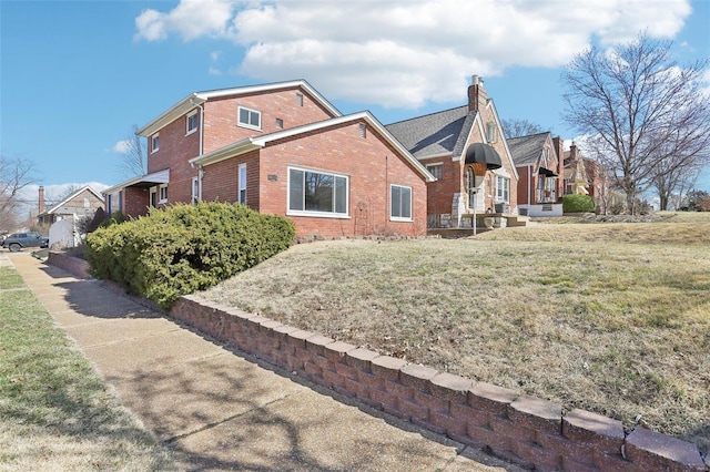 view of home's exterior featuring brick siding, a chimney, and a yard