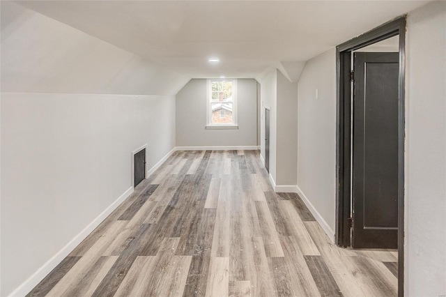 additional living space with light hardwood / wood-style flooring and lofted ceiling