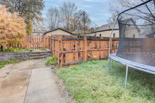 view of yard with a trampoline and a patio