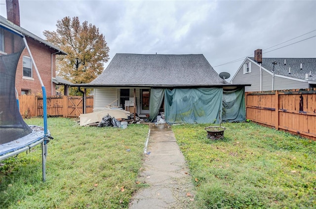 rear view of house featuring an outdoor fire pit, a patio area, a yard, and a trampoline