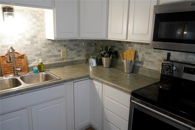 kitchen with backsplash, sink, white cabinets, and stainless steel appliances