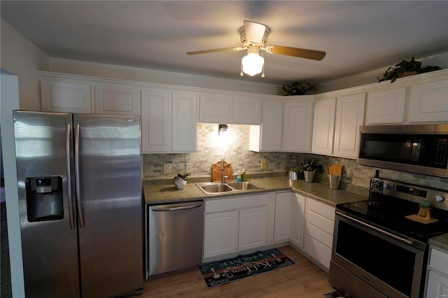 kitchen featuring sink, stainless steel appliances, decorative backsplash, white cabinets, and light wood-type flooring