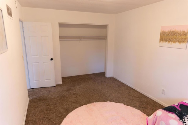 unfurnished bedroom featuring dark carpet and a closet