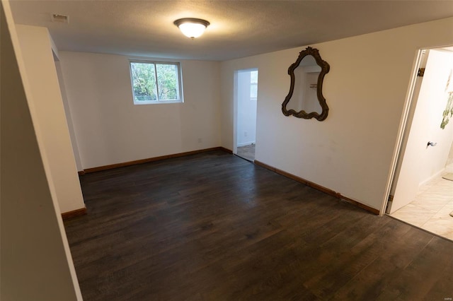 empty room featuring a textured ceiling and dark wood-type flooring