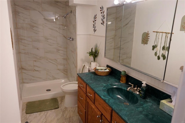 bathroom with a tile shower, vanity, and toilet