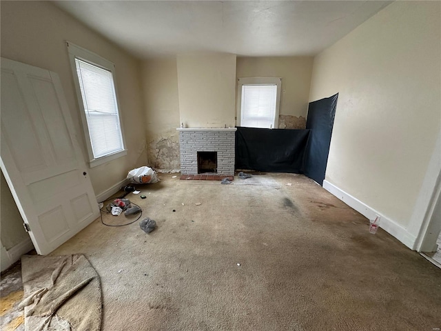 unfurnished living room with a wealth of natural light, a brick fireplace, and carpet flooring