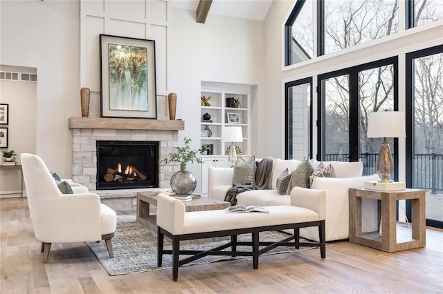 living room with a fireplace, high vaulted ceiling, light hardwood / wood-style flooring, and beamed ceiling