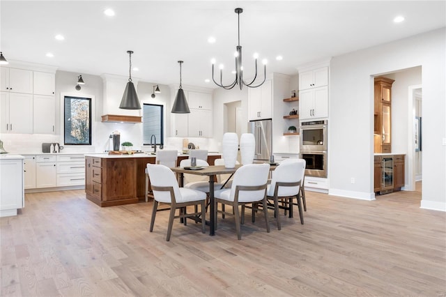 dining space with a chandelier, wine cooler, light hardwood / wood-style flooring, and sink