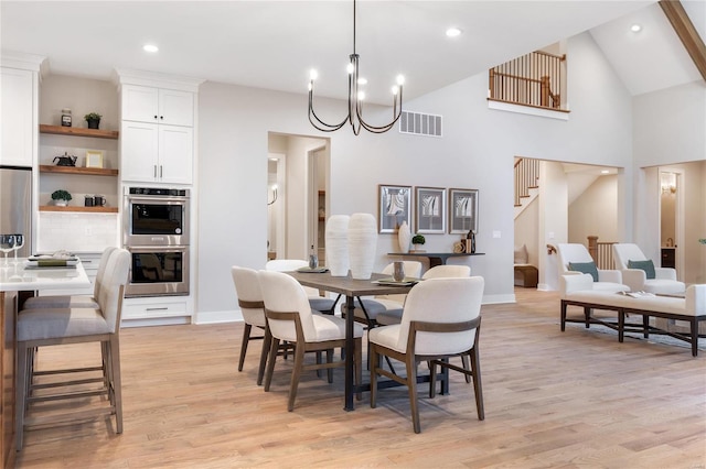 dining area featuring a notable chandelier, light wood-type flooring, and high vaulted ceiling