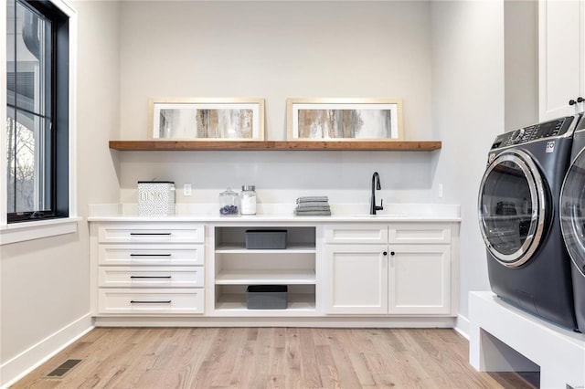 laundry area featuring cabinets, independent washer and dryer, light hardwood / wood-style floors, and sink