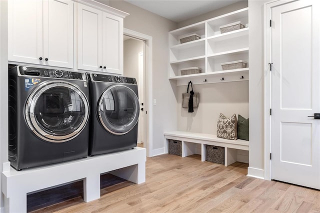 washroom featuring washer and dryer, light hardwood / wood-style flooring, and cabinets